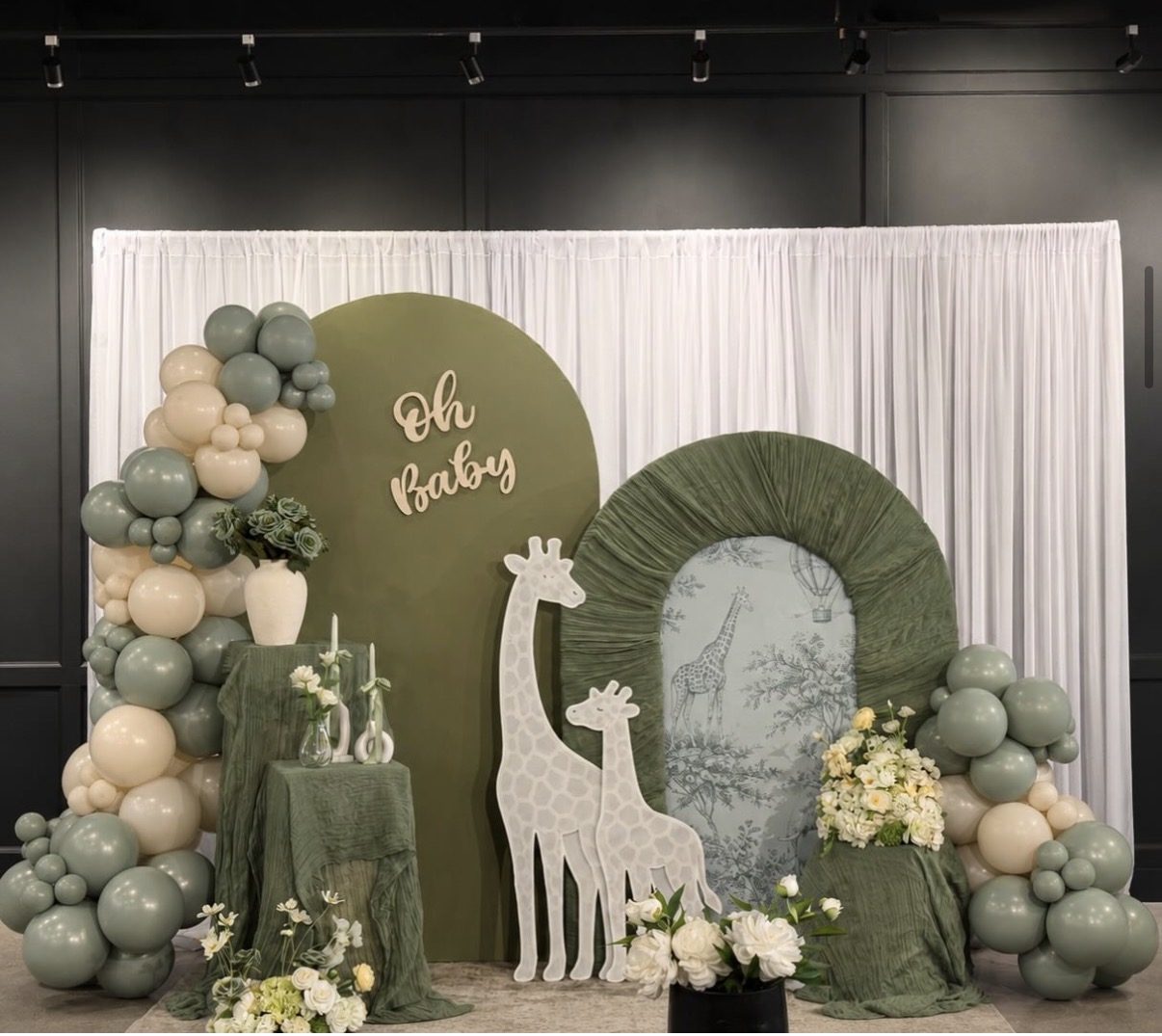 Sage green Oh Baby shower backdrop with giraffe cutouts and balloon garland — baby shower decor rentals Surrey
