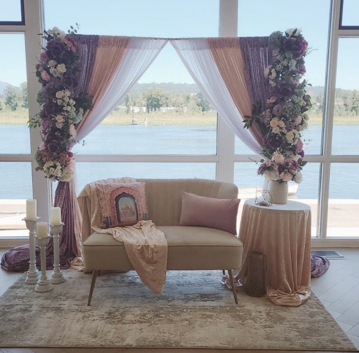 Blush and mauve draped backdrop with florals and a gold velvet loveseat